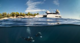 Vue sous-marine d'un catamaran avec plongeurs sous le bateau