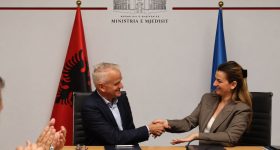 Signature d’une convention de partenariat entre les Explorations de Monaco et l’Albanie, avec une poignée de main entre les représentants devant les drapeaux albanais et européen.